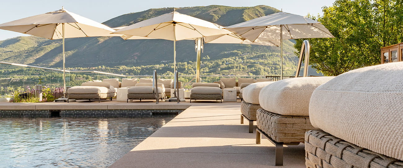 The rooftop pool at the Residences at The Little Nell offers plush patio furniture for guests to relax and enjoy sweeping mountain views.