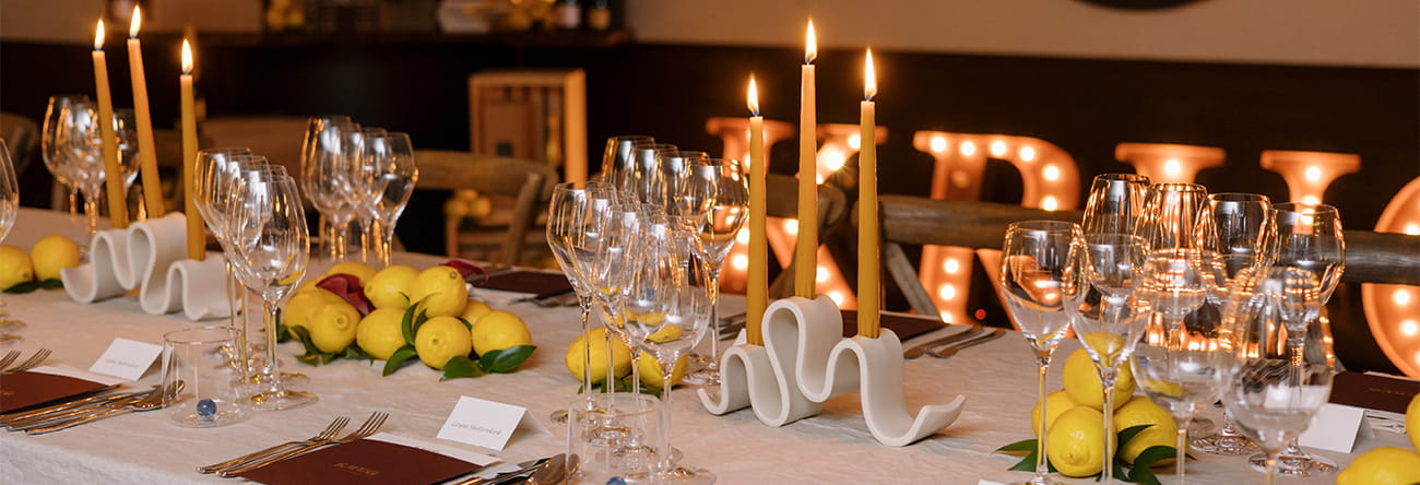 A large table set for a special event dinner with candles and wine glasses.