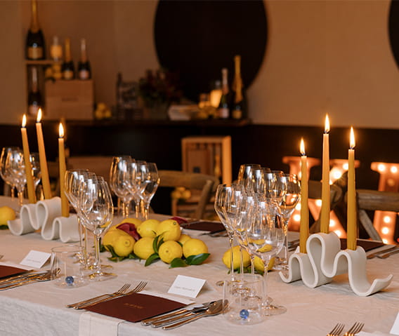A large table set for a special event dinner with candles and wine glasses.