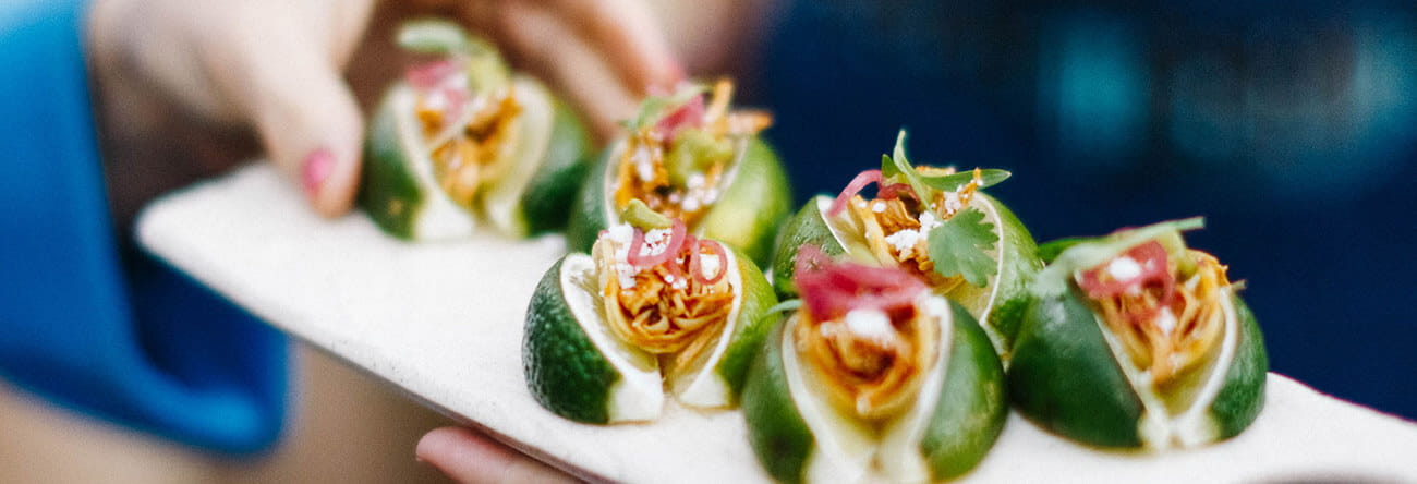 The Little Nell's catering menu offers a variety of delectable bites, like these tacos in tucked between lime wedges.