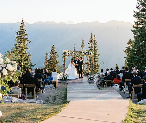 A bride and groom during a ceremony on the top of Aspen Mountain at sunset.