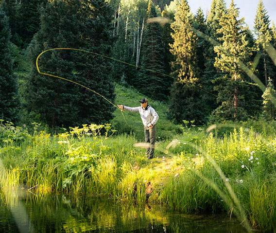 A man fly fishing in the meadows.