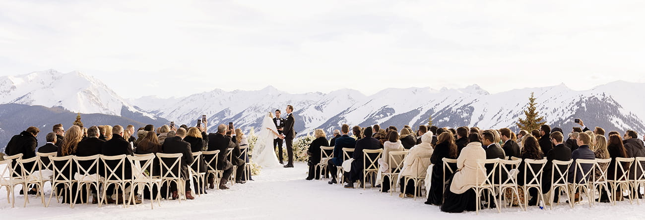 A winter wedding ceremony at the wedding overlook with snowcapped mountains in the background.