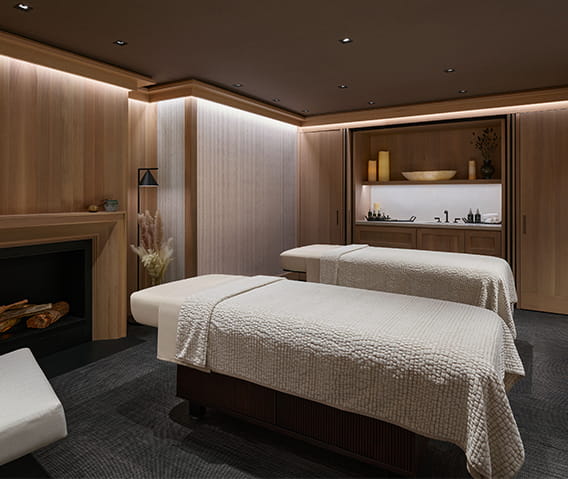 A private treatment room in The Little Nell spa with two massage tables and a fireplace.
