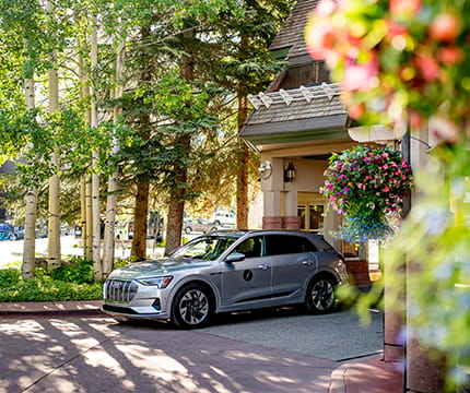 Audi e-tron parked at The Little Nell hotel's front drive with Aspen trees in the background. 