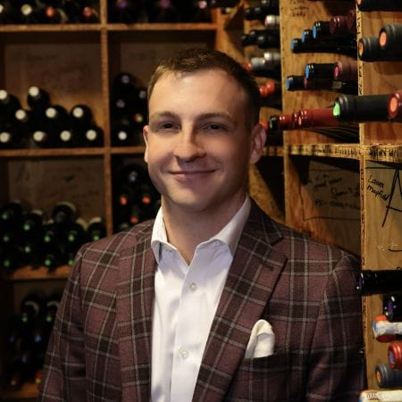 Headshot of a man wearing a suit in a wine cellar