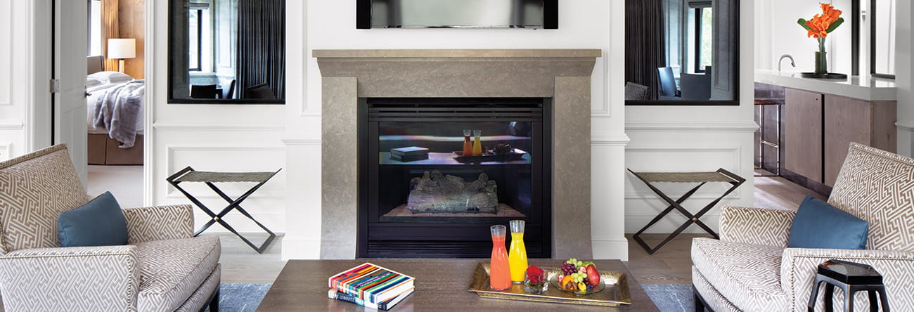 Comfortable seating area with two chairs and a fireplace in The Little Nell's Paepcke Suite.