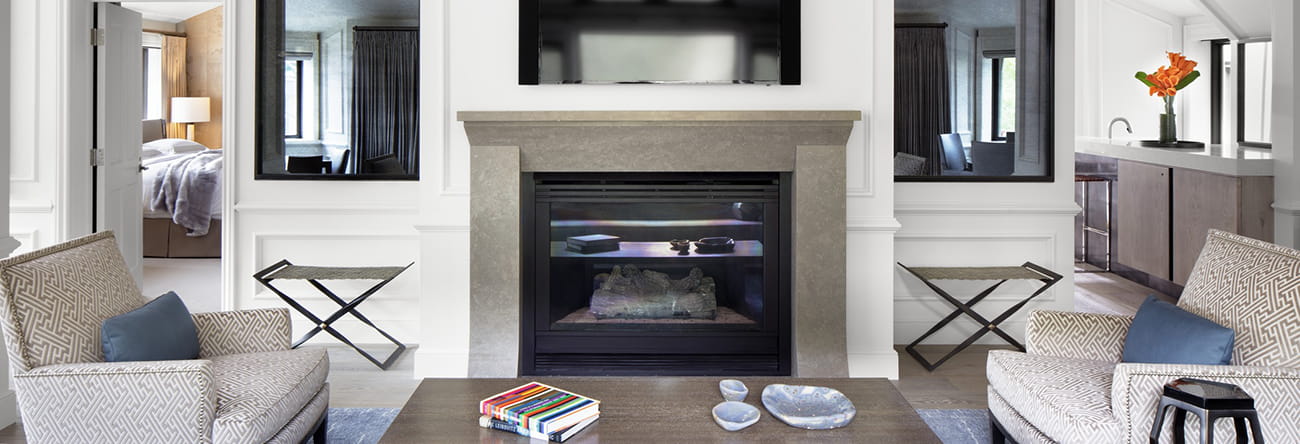 The Paepcke Suite's luxurious living area featuring a cozy gas log fireplace and a flatscreen tv.