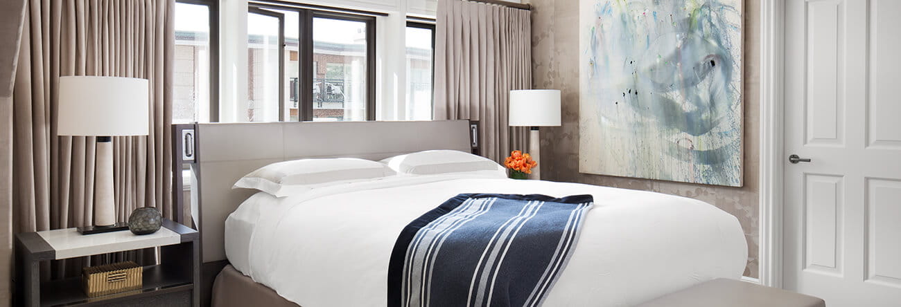 King bed with down comforter and pillows in the bedroom of The Little Nell's Paepcke Suite.