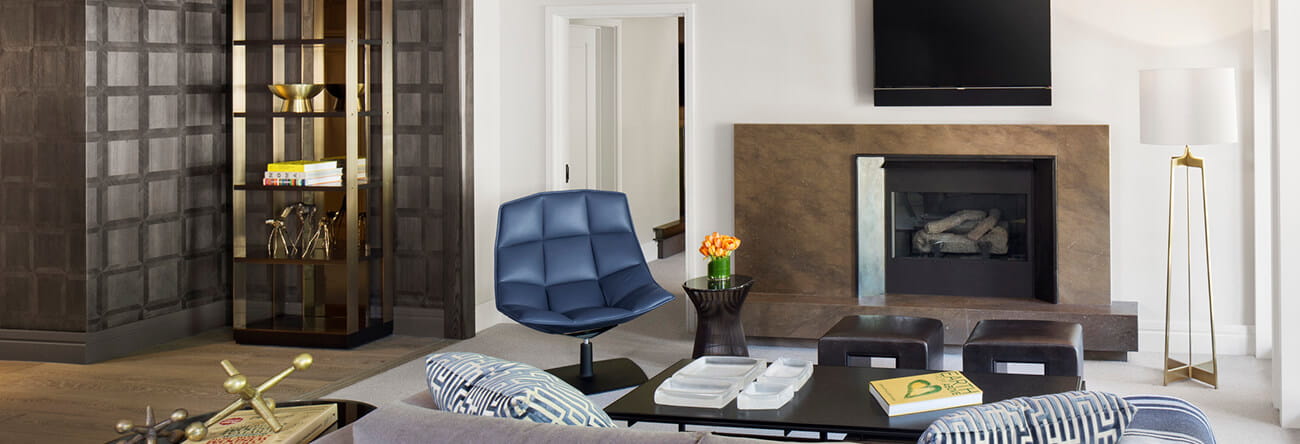 The elegant living room of The Little Nell's Roch Suite with a gas log fireplace and TV.