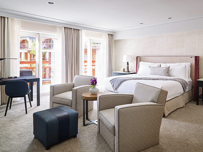 A guest room at The Little Nell with spacious accomodations a balcony, bed, and lounge chairs