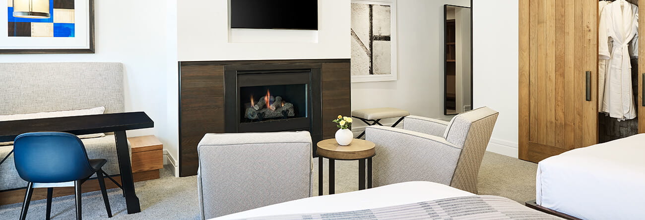 The spacious living area of town side guest room in Aspen featuring a gas log fireplace and flat screen tv.