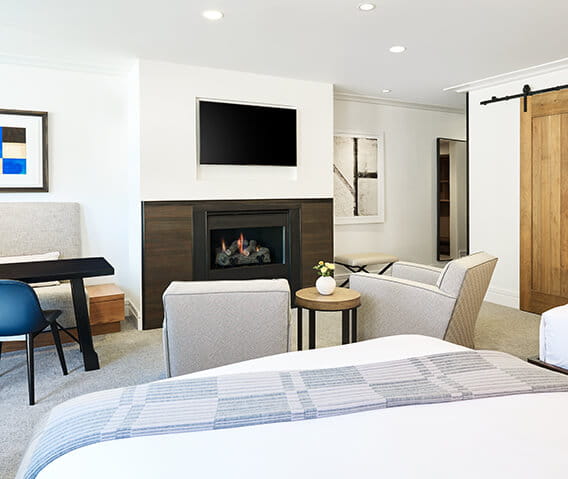 The spacious living area of town side guest room in Aspen featuring a gas log fireplace and flat screen tv.