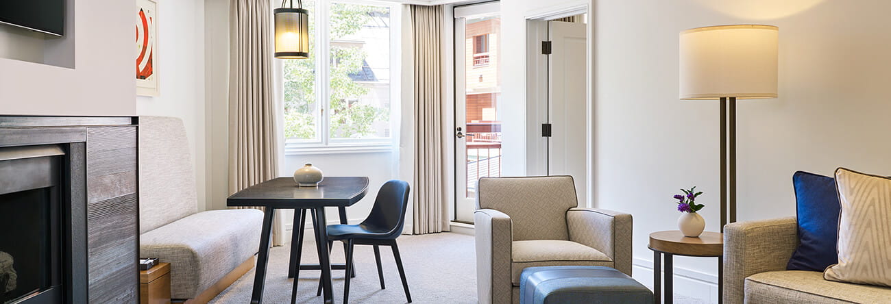 A one bedroom mountain side living area featuring ample seating and a scenic view of Aspen Mountain.