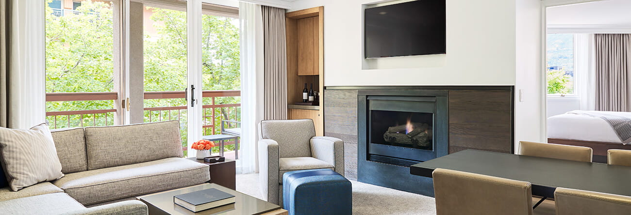Living room of a two bedroom town side suite at The Little Nell with a fireplace and dining table.