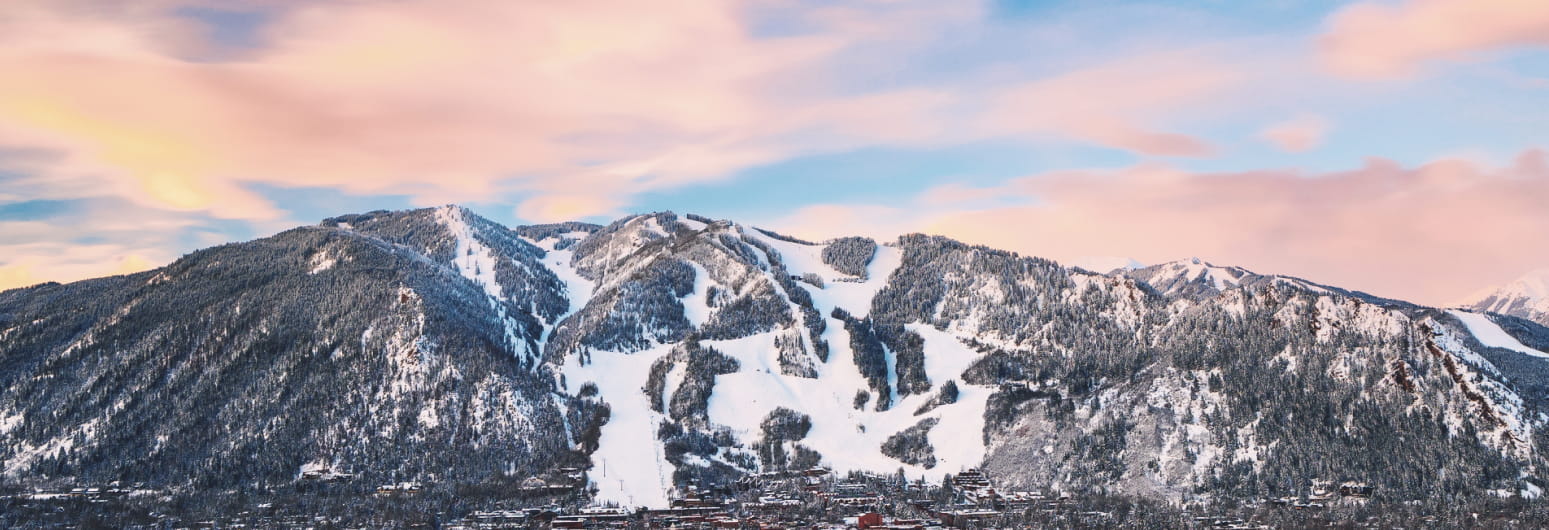 Pink clouds over Aspen Mountain during the winter with snow 