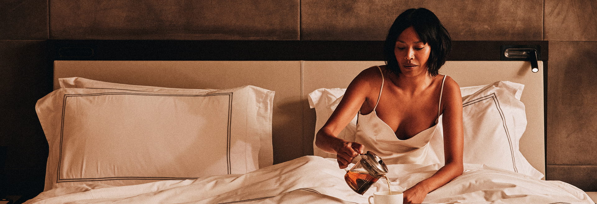 woman on hotel bed eating breakfast