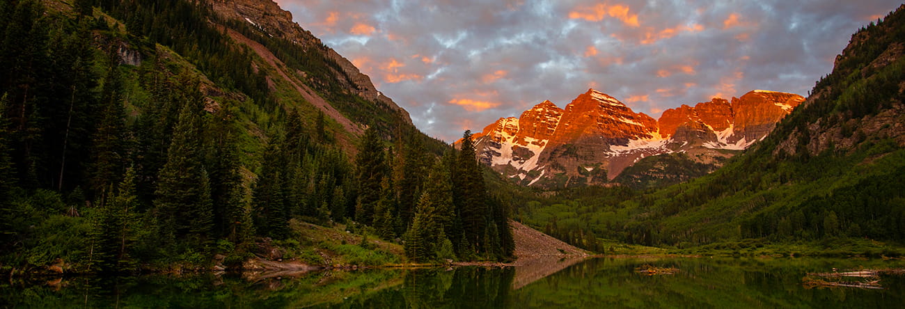 The sun sets on a scenic view of Aspen's Maroon Bells in the summer.