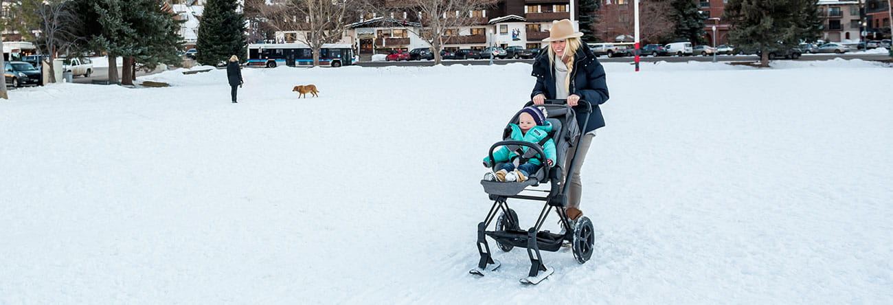 A mom and daughter enjoy The Little Nell's family amenities on a walk with a ski stroller.