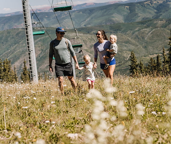 Parents with two children take a walk beneath the Silver Queen Gondola in Aspen.
