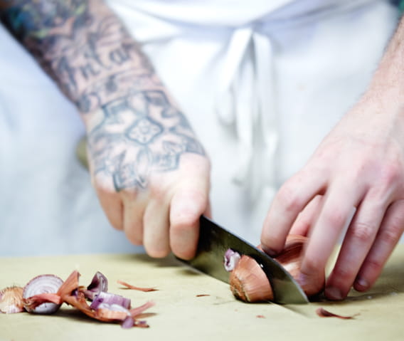 Person chopping an onion at Aspen restaurant.