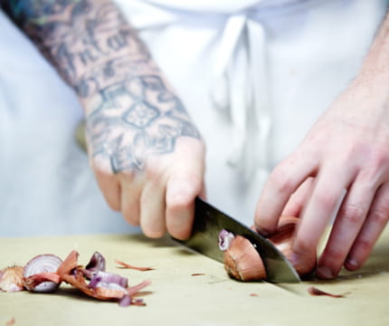 Person chopping an onion at Aspen restaurant.