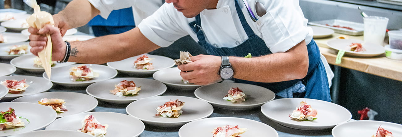 chef decorating a dish with piping bag.