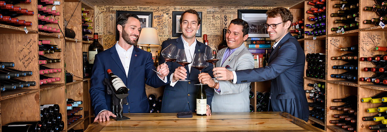 The Little Nell's knowledgeable team of sommeliers cheers with glasses of red wine.