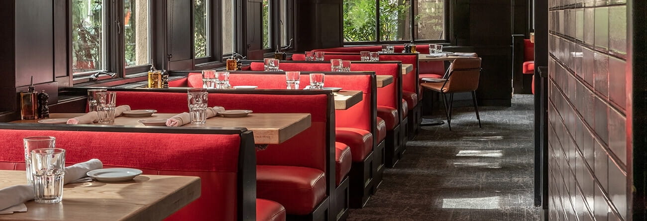 Red dining booths with table settings at AJAX Tavern in Aspen, Co.