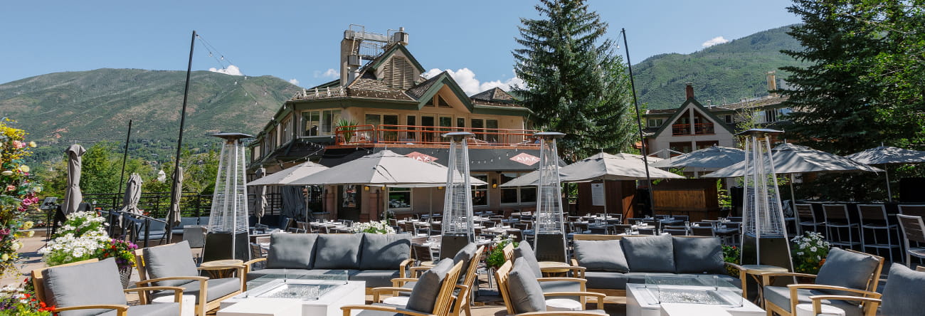 The sunsoaked patio of Ajax Tavern with stunning mountains in the background.