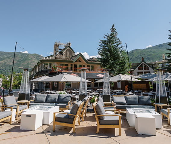 The sunsoaked patio of Ajax Tavern with stunning mountains in the background.