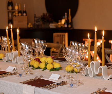 A large table set for a special event dinner with candles and wine glasses.