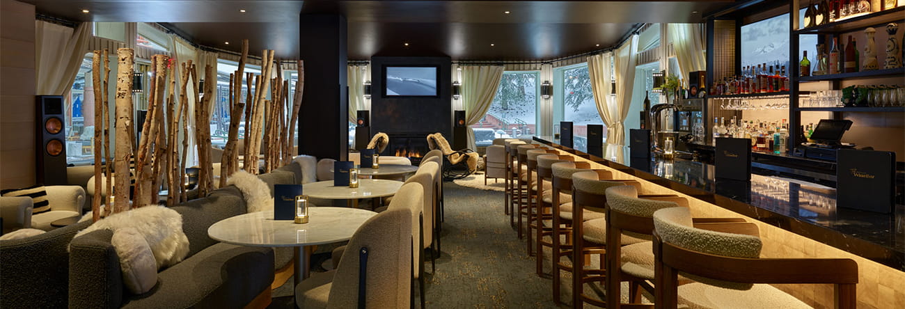 The Little Nell Wine Bar with plush couch seating, a complete bar, TV's, and fire place. 