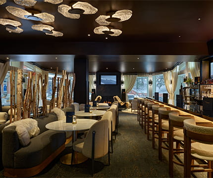 The Little Nell Wine Bar with plush couch seating, a complete bar, TV's, and fire place. 