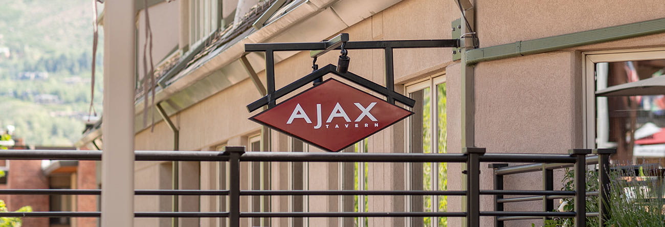 Ajax Tavern restaurant sign on the patio in summer. 