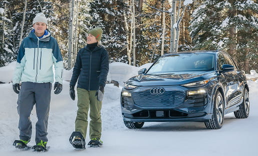 couple snowshoeing by audi car