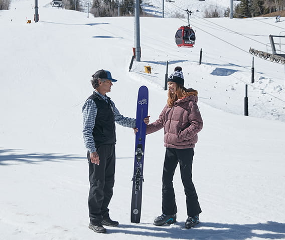 A member of the ski concierge team giving a guest her skiis.