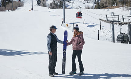 A member of the ski concierge team giving a guest her skiis.