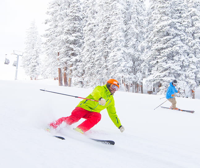Two guests enjoy skiing in Aspen with winter adventures at The Little Nell.