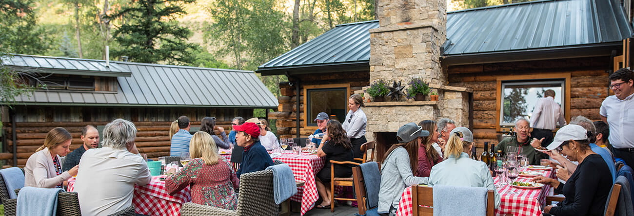 A group of people eating dinner on the patio at Mad Dog Ranch, where guests enjoy an al fresco dinner following a bike ride from the hotel.