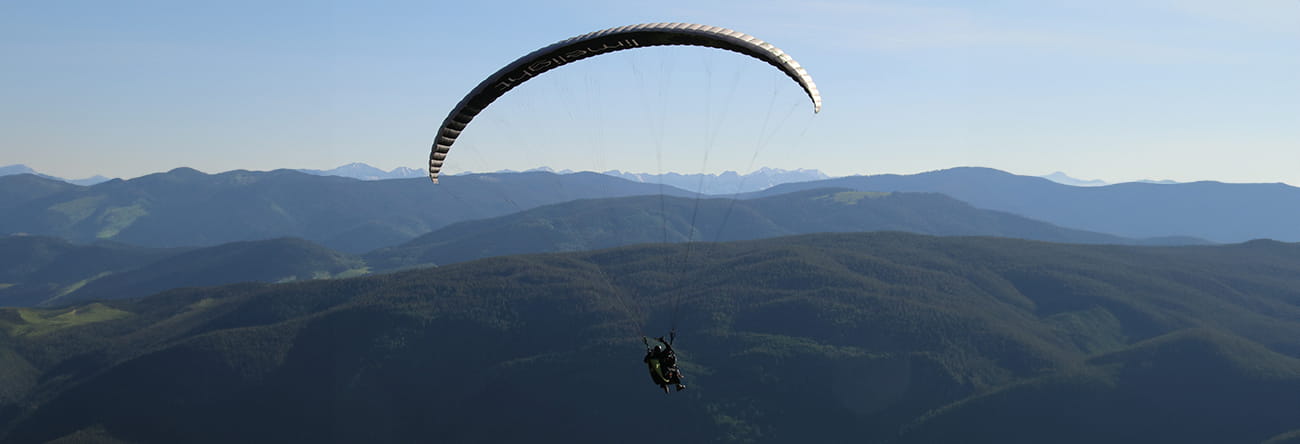 A paraglider in the sky overlooking the mountains surrounding Aspen.