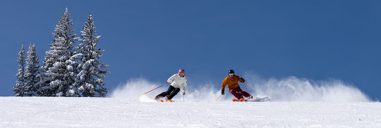 man and woman skiing on aspen mountain.