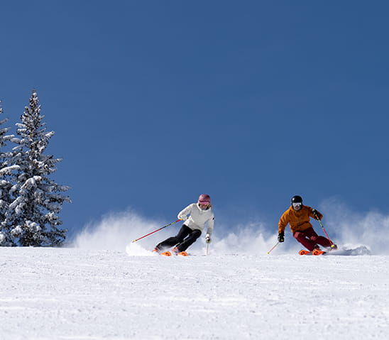 man and woman skiing on aspen mountain.