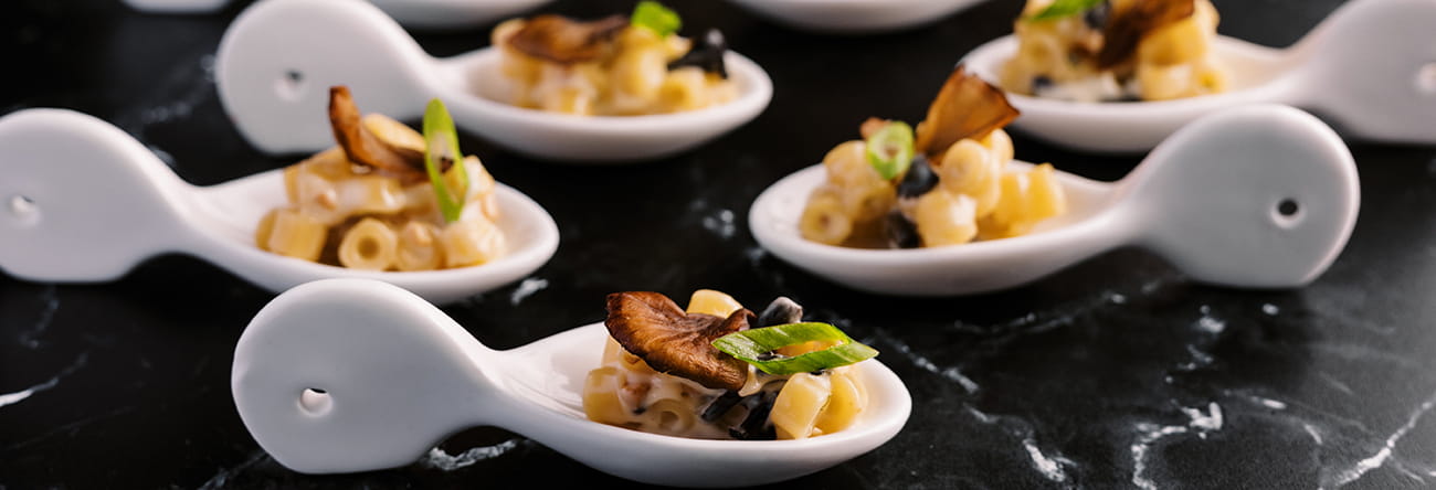 Gourmet truffle mac and cheese bites served on white bite sized spoons.