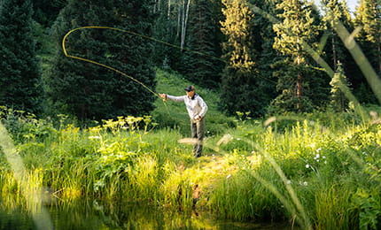 A man fly fishing in the meadows.