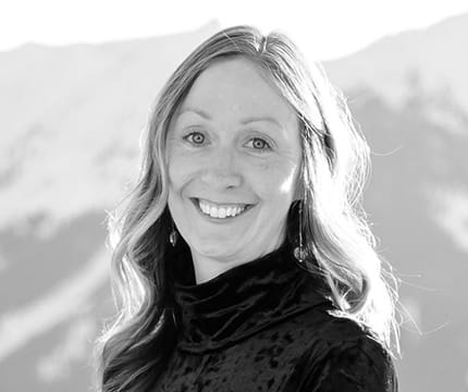 Headshot of Events Manager, Jessica Hollinger in black and white with mountain peaks in the background.
