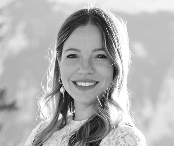 Black and white headshot of Events Director, Emily Alexander with mountain peaks in the background.