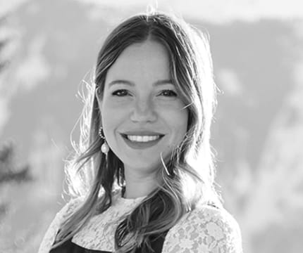 Black and white headshot of Events Director, Emily Alexander with mountain peaks in the background.