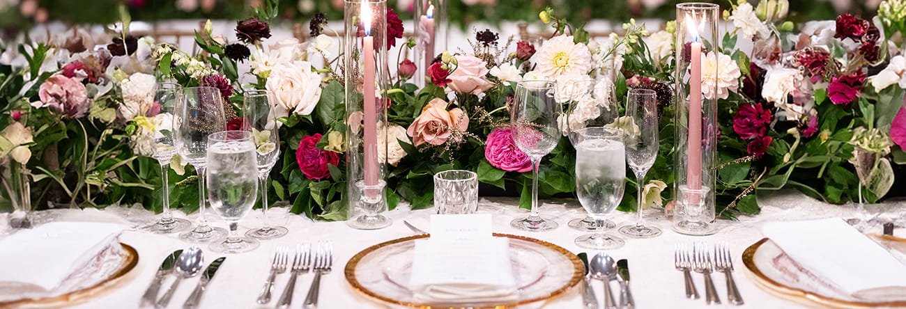 A banquet table set with a plethora of flowers and fine china. 