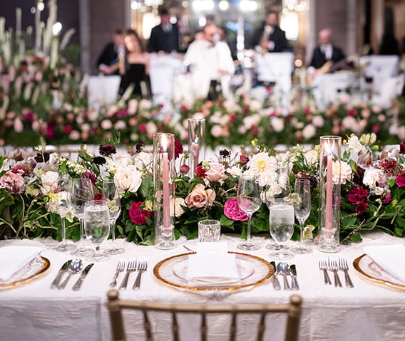 A banquet table set with a plethora of flowers and fine china. 
